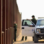 Appeals Shock: Court Restores Key Immigration Enforcement Tool Border patrol agents near a tall metal fence.