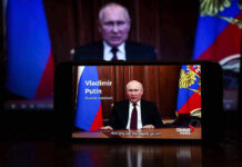 Man speaking on screen with Russian flag background.