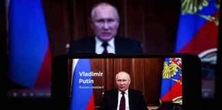 Calls With Putin Raise Peace Hopes—No Deal Yet Man speaking on screen with Russian flag background.