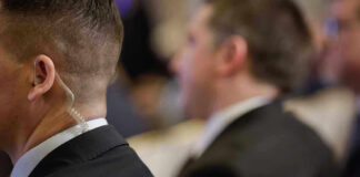 Federal Probe Targets Political Betting Market Over Trades Security personnel with earpiece in a suit.