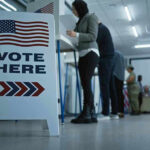 Sign reading Vote Here in a polling station.
