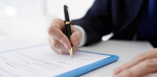 Banks Hint: Stocks Are the Sucker Bet Person signing a document with a pen.