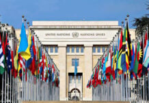 U.S.–Iran Agreement Nears, but Core Terms Still Undecided United Nations building with numerous national flags outside.