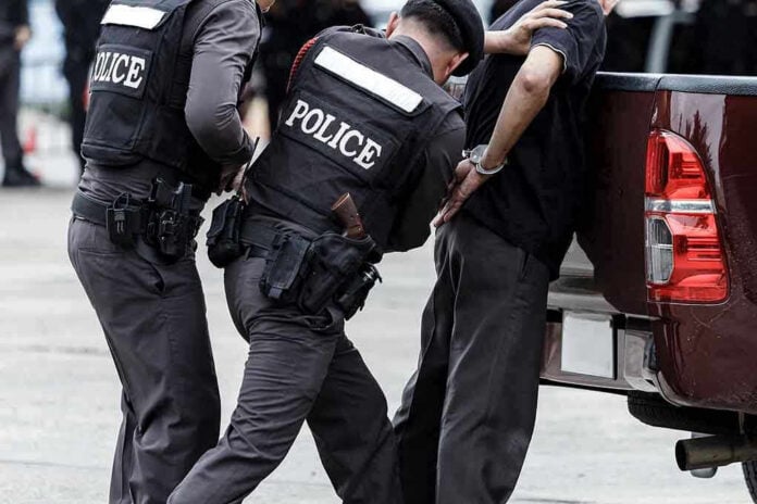 Police officers arresting a handcuffed person.