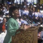 The ‘First Black President’ Debate Returns A woman passionately speaking at a political rally in front of a large crowd