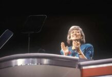 Energy Bills Surge as Britain Feels Global Fallout A female speaker on stage smiling and clapping during a presentation