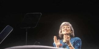 Energy Bills Surge as Britain Feels Global Fallout A female speaker on stage smiling and clapping during a presentation