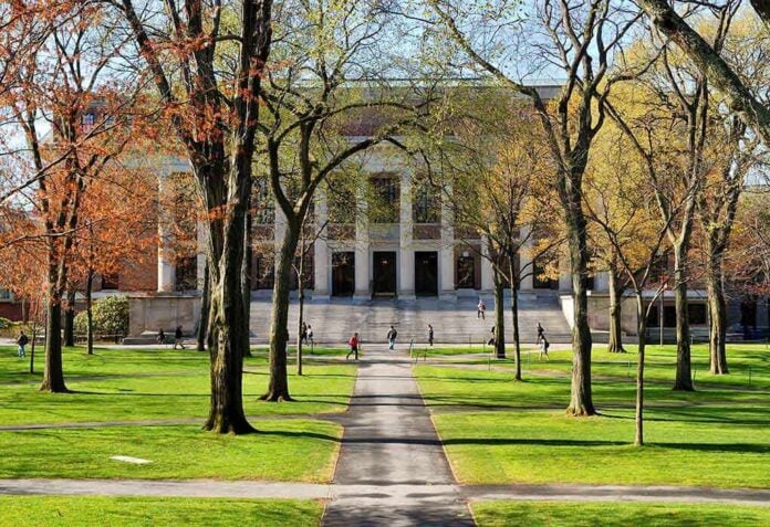 shutterstock_131270519 Students walking on a university campus with autumn trees and a historic building in the background