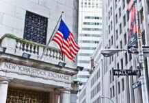 Deal Still Unclear: Dow Hits Record on Iran Peace Hype, Facade of the New York Stock Exchange with an American flag and Wall Street sign