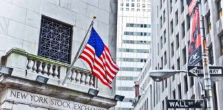 Deal Still Unclear: Dow Hits Record on Iran Peace Hype, Facade of the New York Stock Exchange with an American flag and Wall Street sign