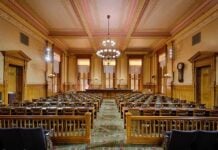 Intelligence Office Cuts Bloat by 40% Interior view of a historic courtroom with wooden furnishings and chandeliers