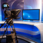 Familiar NFL Voice Leaves Game Calls Behind After ESPN Deal TV studio with camera and empty anchor desk.