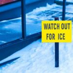 yellow warning sign in snow near walkway