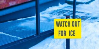 yellow warning sign in snow near walkway