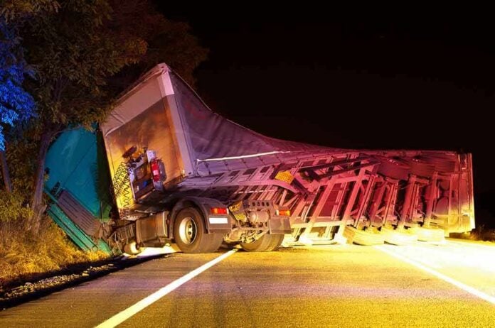 shutterstock_115026379 An overturned truck on the side of the road at night with emergency lights