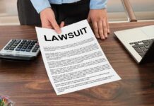 Person holding a lawsuit document on a wooden desk