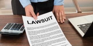 Person holding a lawsuit document on a wooden desk