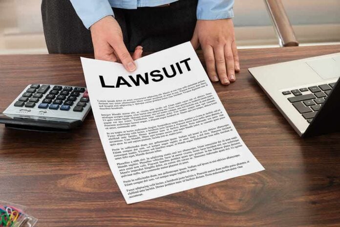 Person holding a lawsuit document on a wooden desk