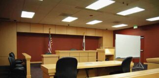 Justice Department Revives Long-Dormant Law Interior view of an empty courtroom with wooden furniture and American flags