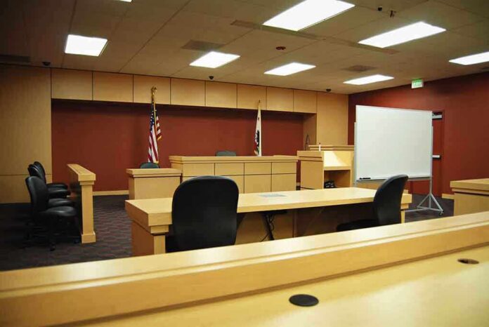 shutterstock_6768826-1 Interior view of an empty courtroom with wooden furniture and American flags