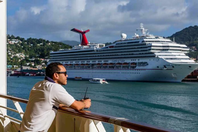 Man leaning on ship railing looking at a docked cruise ship