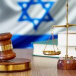 Gavel and scales of justice with Israeli flag in background