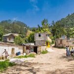 Rural village street with people gathered and hills in the background