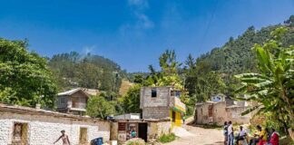 Family Trapped: American Flies to West Bank Rural village street with people gathered and hills in the background