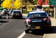Police cars with flashing lights near school buses on a city street