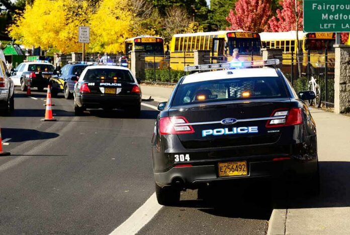 shutterstock_117302929 Police cars with flashing lights near school buses on a city street