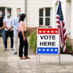 Voters wearing masks line up outside a polling place