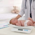 Pediatrician weighing a baby on an infant scale