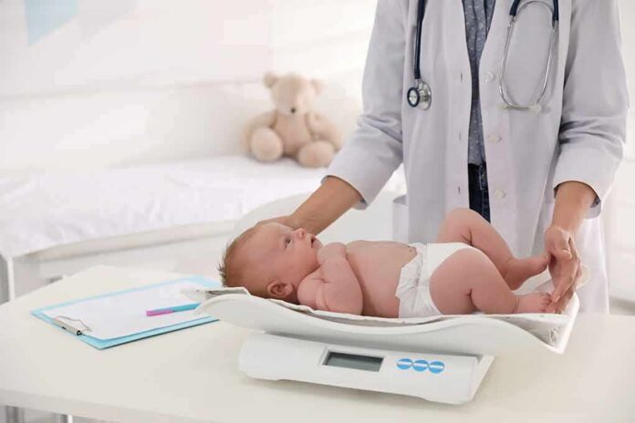 shutterstock_1803592981 Pediatrician weighing a baby on an infant scale