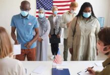 Michigan Muslim Voting Data Reveals Split Protest Voters wearing masks stand in line at a polling station