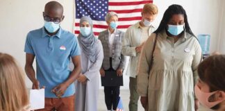 Voters wearing masks stand in line at a polling station
