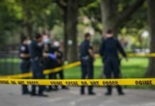 crime scene tape with police officers in a park