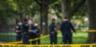 crime scene tape with police officers in a park