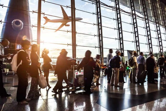 shutterstock_210042967 Passengers queue inside an airport terminal at sunset