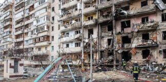 Damaged apartment building behind a playground slide