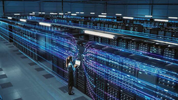 Technician with laptop in a large data center aisle