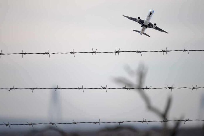Airplane taking off above barbed wire fence
