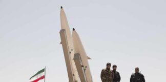 Iran Offers $30K Bounty for U.S. Troops soldiers stand beside large missiles at outdoor display