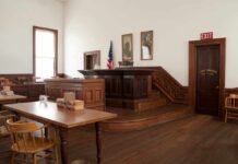 Convicted Rapist Could Seek Parole After Months Interior of a historic courtroom with wooden furniture and an American flag