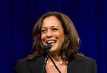 Smiling woman speaking at a podium with microphones.