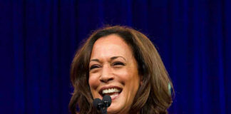 Smiling woman speaking at a podium with microphones.