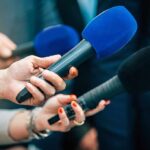 South Bronx Outbreak Under Investigation Reporters holding colorful microphones