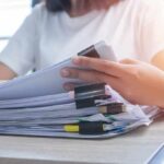 Person organizing a stack of documents with binder clips
