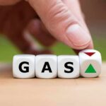 Hand flipping dice showing gas with up and down arrows