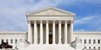 Front view of the Supreme Court building with large columns and steps under a blue sky