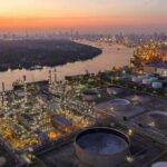 New Trump Threat Puts Iran’s Civil Infrastructure Industrial oil refinery complex beside a river at dusk